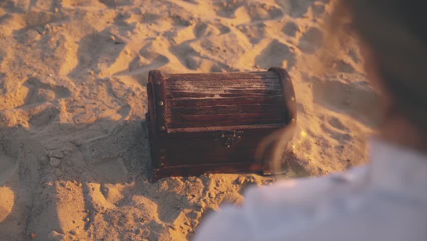 unrecognizable person close-up hands open treasure chest gold coins glowing in sun light. Fantasy thief pirate finds treasure wooden box old style full of rich jewelry. Nature sand desert island 4k.