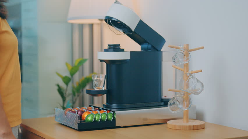 hand making Espresso Coffee by Coffee Maker Machine with Capsule of roasted coffee bean on wood table bar. Daily beverage drink at Home, Apartment and Office concept