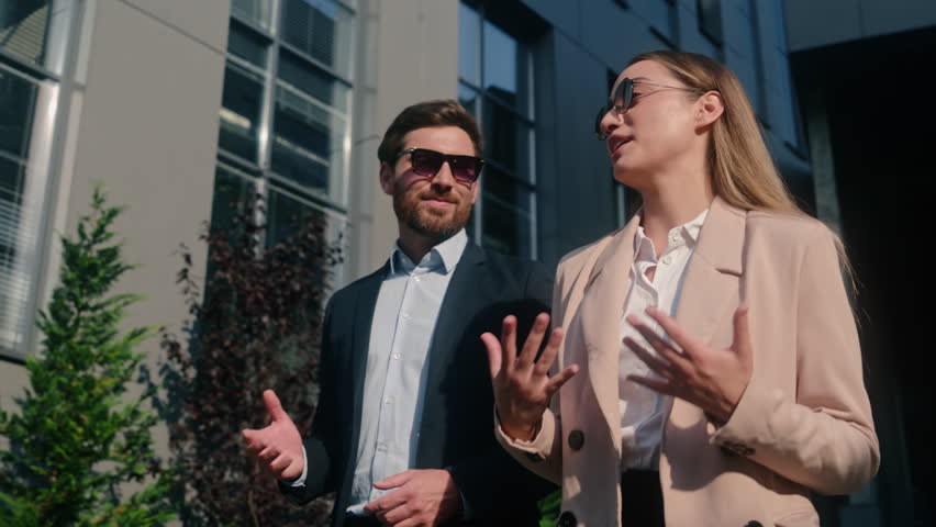 Two business people happy smiling friendly Caucasian businessman male man guy businesswoman woman female girl employers in stylish sunglasses partnership talking communicate walking in city working