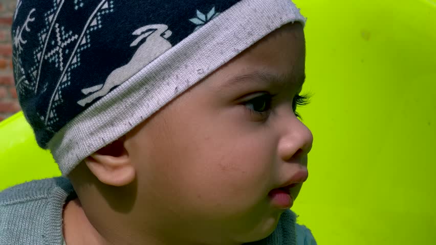 A muslim new born boy in an open air park smiling, looks beautiful an Indian organ face. A healthy boy child