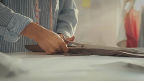 In a well-lit workshop, someone focuses on cutting fabric with scissors, preparing for a sewing project. The workspace is organized with tools and materials all around, showcasing creativity - Powered by Shutterstock - Get 15% off with code: PIKWIZARD15