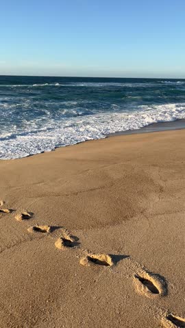 footprints on the beach and light waves