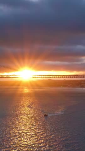 View of 25 de Abril Bridge famous tourist landmark of Lisbon connecting Lisboa and Almada on Setubal Peninsula over Tagus river on sunset. Lisbon, Portugal. Camera pan
