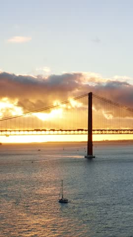 View of 25 de Abril Bridge famous tourist landmark of Lisbon connecting Lisboa and Almada on Setubal Peninsula over Tagus river on sunset. Lisbon, Portugal