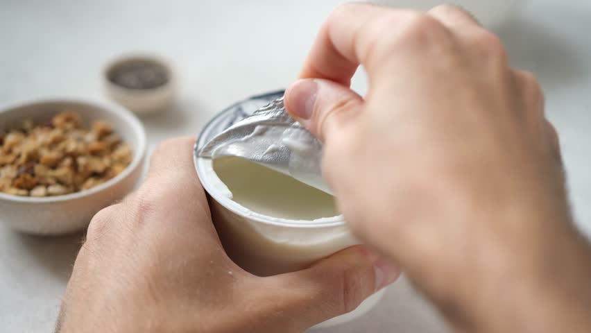 Plain greek yogurt in a plastic cup. Open lid 