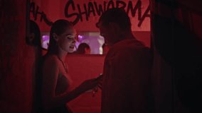 Couple exchanging phone numbers at romantic meeting under neon club lights closeup. Young clubbing pair enjoy intimate communication in vibrant nightlife. Smiling woman talking with man in hallway. - Powered by Shutterstock - Get 15% off with code: PIKWIZARD15