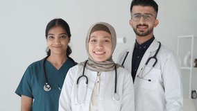 Pretty islamic muslim happy female doctor standing next to colleagues doctors. Medical services and insurance. Arabian Middle Eastern mixed race doctors interns staff - Powered by Shutterstock - Get 15% off with code: PIKWIZARD15