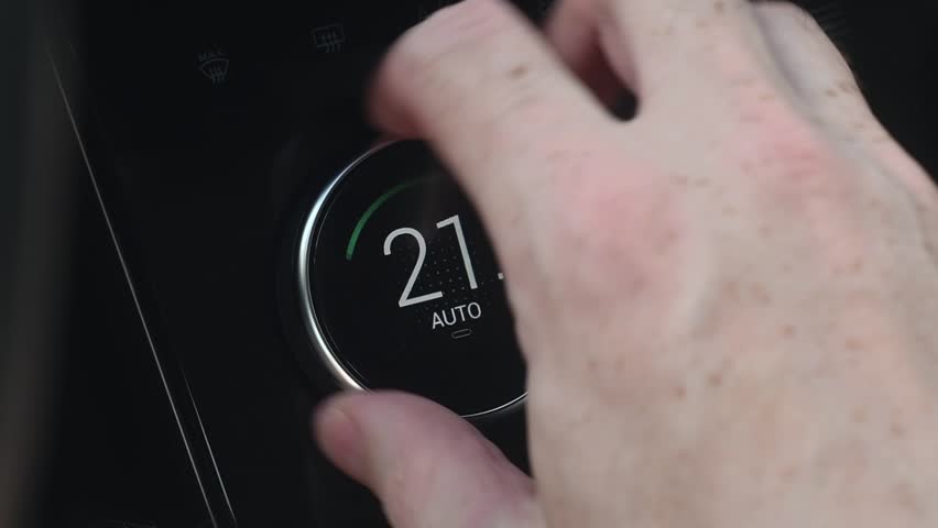 Man's hand turns the air conditioner on-off ring of a modern car. Man setting the temperature in the interior of the car. Climate control in the car.