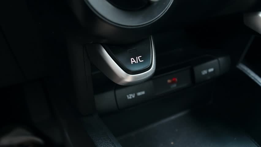 Man's hand presses the button to turn on the air conditioner in the car.