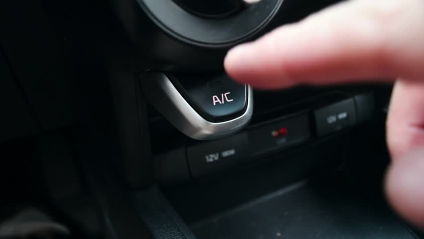 Man's hand presses the button to turn on the air conditioner in the car.
