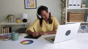 Young African American graphic designer wearing headphones is drawing on a tablet next to her laptop. 4k resolution video. - Powered by Shutterstock - Get 15% off with code: PIKWIZARD15