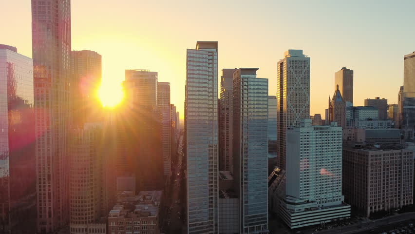 Chicago skyscrapers at sunset with warm reflections. Sunset view of Chicago's skyscrapers, with warm sunlight reflecting on glass facades and casting shadows, creating a serene urban atmosphere.