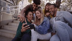Diverse group of university friends sitting on stairs in street city. Happy students using and looking smartphones while smiling thrilled and excited. Chatting and commenting fun things in mobiles. - Powered by Shutterstock - Get 15% off with code: PIKWIZARD15