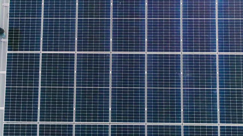 Photovoltaic solar panels on roof get clean energy from the sun. Slow motion. Aerial view. Solar Panel Array. Drone Aerial View of Modern Photovoltaic Electricity System, Close Up.