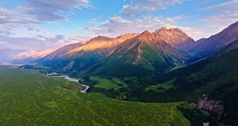 Curved river and green grassland with mountain natural landscape at sunset in Xinjiang. Beautiful scenery along the Duku Highway in China.