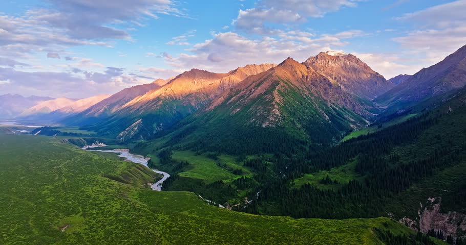 Curved river and green grassland with mountain natural landscape at sunset in Xinjiang. Beautiful scenery along the Duku Highway in China.