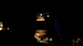 Nighttime recording scene, capturing a person filming with a smartphone, focusing on bokeh lights and reflections on the screen. Abstract urban nightlife ambiance. - Powered by Shutterstock - Get 15% off with code: PIKWIZARD15