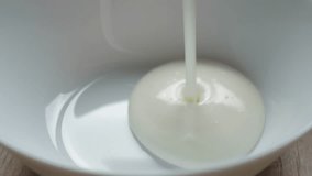 Milk yogurt white color pour into white glass bowl close-up. Stream of cream falling into bowl. Dairy products. Fresh pasteurized cream pouring into bowl to combine with granola for breakfast - Powered by Shutterstock - Get 15% off with code: PIKWIZARD15