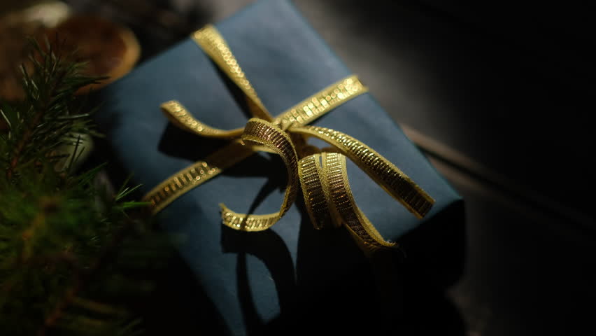 Luxury Christmas present. Elegant Christmas gift box wrapped in dark blue paper decorated golden ribbon.