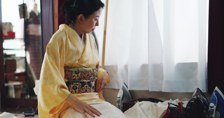Japanese, clothes and woman folding kimono with fabric, measurement and textile design in home. Silk pattern, seamstress and girl on floor with Asian culture, traditional fashion and vintage style