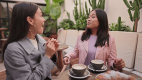 Two diverse young women share a joyful conversation while enjoying coffee together, surrounded by a warm and friendly atmosphere. - Powered by Shutterstock - Get 15% off with code: PIKWIZARD15