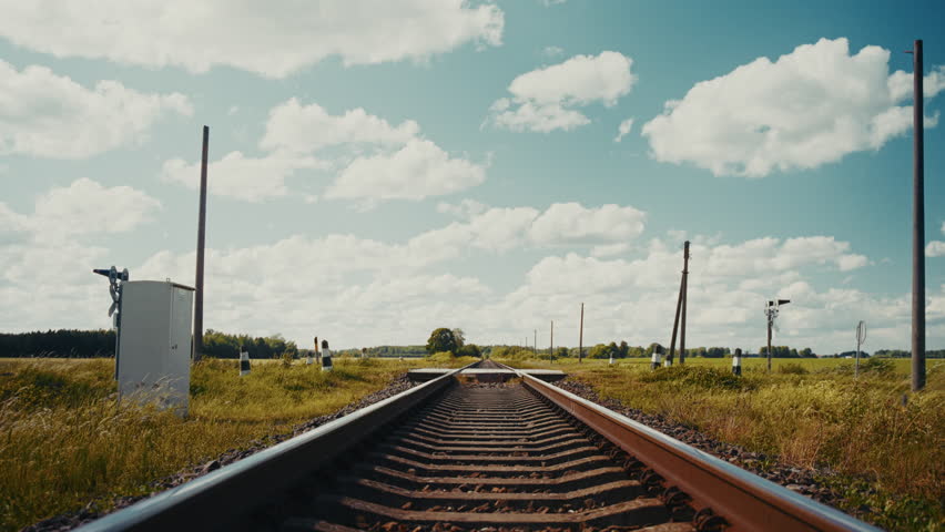 Semi truck crossing a rural railroad in the countryside during summer with white clouds in the blue sky