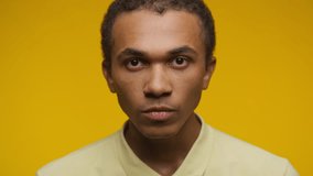Serious man in yellow shirt with intense gaze against yellow background - Powered by Shutterstock - Get 15% off with code: PIKWIZARD15