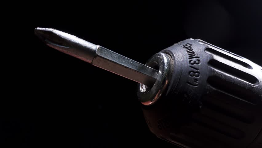 Macro view of a specialized screw tip, showing a spinning screwdriver bit attached to a power drill in action. Construction concept.