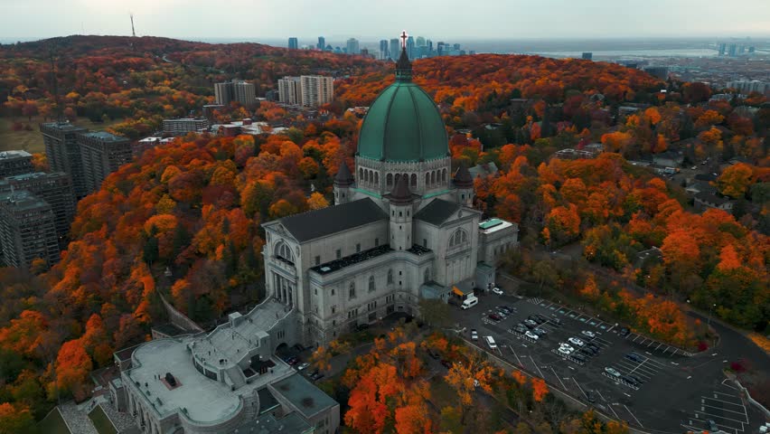 aerial shot around Saint Joseph Oratory in Montreal city with the skyline in the backgound and colorful trees at fall season on an overcast day, Quebec Province, Canada