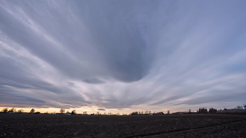Timelapse of mooving clouds over field before sunset in Southern Norway