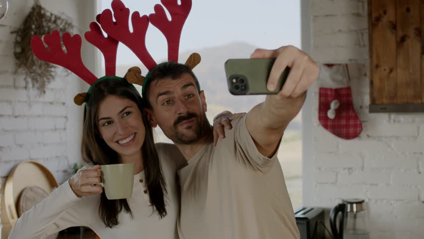 Loving couple enjoy Christmas morning in their cozy kitchen, drinking coffee, sharing hugs, and laughing. 4k video