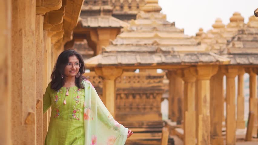 Portrait of Indian young woman in traditional salwar suit in Bada Bagh at Jaisalmer, Rajasthan, India. Tourist exploring old historical landmark. Tour, tourism and travel concept