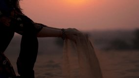 Sunset silhouette shot of desert sand falling from Indian woman's hand at Thar desert, Jaisalmer, Rajasthan, India. Sunset sky and desert sand. Travel and holidays concept. - Powered by Shutterstock - Get 15% off with code: PIKWIZARD15