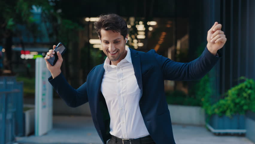 Cheerful Young Man After Work Happy Dancing Walking Outside. Funny Crazy Dancer with Earphones Jumping Celebrates Victory, Success. People and Emotions Concept