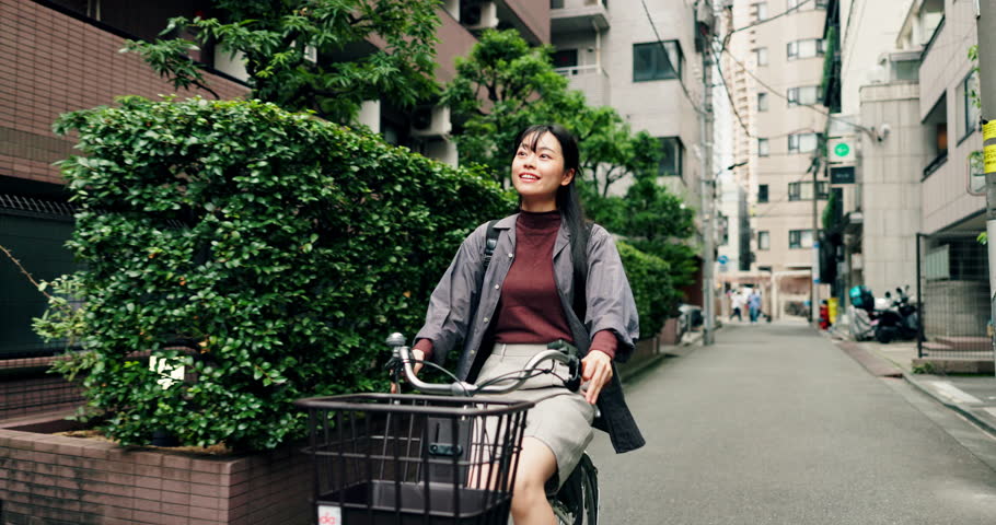 Woman, riding and bicycle in city for commute, location and positive with joy, travel and trip. Asian person, happy and bike in urban town for eco friendly transport, exercise or morning in Japan