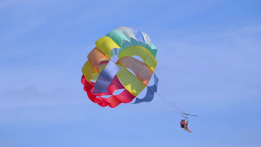 Thrilling experience of parasailing, offering tourists a breathtaking view from the sky, over the sparkling sea in 4k slow motion 60fps