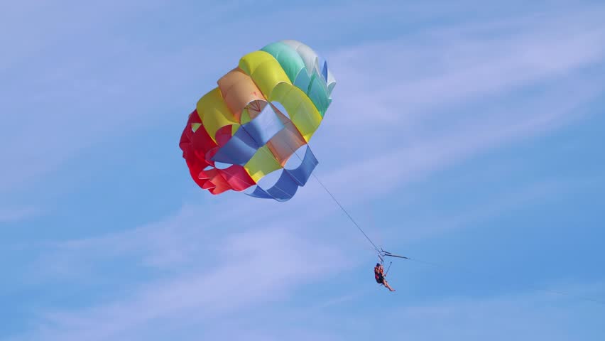 Thrilling experience of parasailing, offering tourists a breathtaking view from the sky, over the sparkling sea in 4k slow motion 60fps