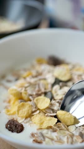 Spoon takes yogurt mixed with granola and cereal in a bowl in the process of eating food. Breakfast natural muesli mixed with cream and using a spoon. Vegetarian food and healthy diet. vertical