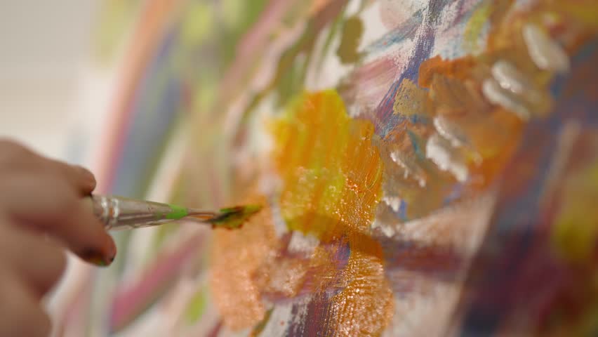Art therapy in psychology, closeup view of paintbrush in artist hand and canvas. Painter applying bright colors on paper sheet, drawing abstract style picture in workshop, hobby, passion, profession
