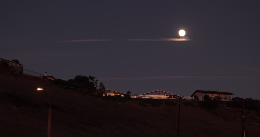 The moon rises over houses in a neighborhood of Rancho Palos Verdes, California, USA.