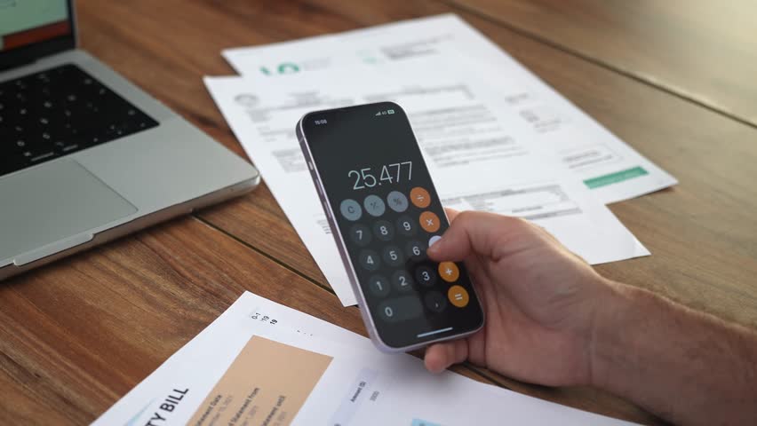 Businessman reviews utility bills subtracting specific items from total quantity on phone, elderly man calculates household finances analyzing papers slow motion