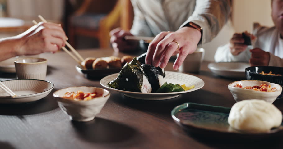 Food, sushi and hands of people at table with Asian cuisine, seafood and dumplings for eating together. Family, healthy and closeup of Japanese meal for nutrition at lunch, dinner and supper in home