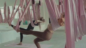 Group of women engages in an aerial yoga class, using hammocks for support and flexibility in a bright and inviting studio space - Powered by Shutterstock - Get 15% off with code: PIKWIZARD15