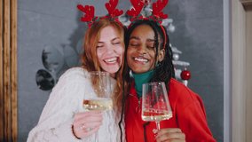 Two joyful women in festive reindeer antlers celebrate with sparkling drinks in front of a beautifully decorated Christmas tree filled with cheerful lights and ornaments - Powered by Shutterstock - Get 15% off with code: PIKWIZARD15