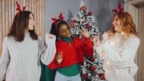 In a cozy holiday room, three friends dance with laughter, wrapped in sparkling garlands. Christmas decorations add a festive charm as they celebrate with joy and warmth - Powered by Shutterstock - Get 15% off with code: PIKWIZARD15