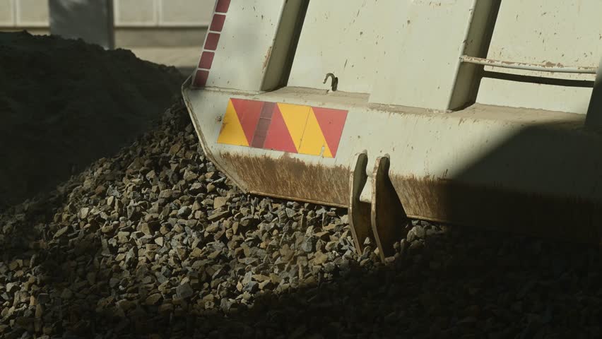 Truck unloading crushed stone gravel on construction site, slow motion 4K with selective focus