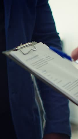 Vertical video Showroom dealer completes paperwork after selling vehicle, shaking hands with buyer and offering car keys. Salesman in dealership signing contract with man, reaching agreement, camera A