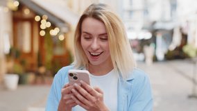 Oh my God Wow. Excited happy joyful winner young woman using smartphone looking at screen browsing celebrating win good message news. Caucasian lady traveler with mobile phone in urban street outdoors - Powered by Shutterstock - Get 15% off with code: PIKWIZARD15