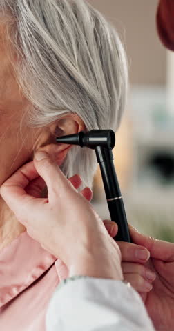 Healthcare, hands of doctor and patient ear in hospital for check up, diagnosis or hearing loss exam. Closeup, elderly woman or audiologist in practice with otoscope, tinnitus symptoms or appointment