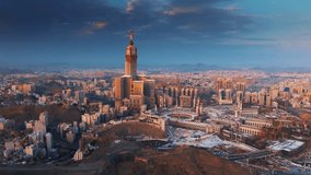 Aerial view of the Abraj Al-Bait Clock Tower and Grand Mosque in Mecca illuminated by the golden light of sunrise, surrounded by the sprawling holy city and mountains - Powered by Shutterstock - Get 15% off with code: PIKWIZARD15